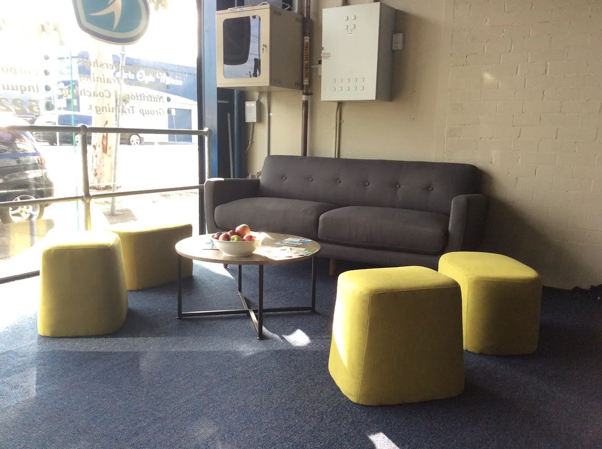 The member lounge with a grey sofa and yellow ottomans